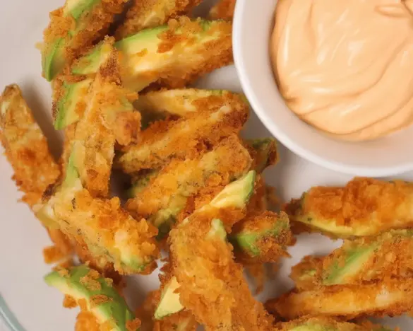 Crispy Air Fryer Avocado Fries served with a dipping sauce on a plate.