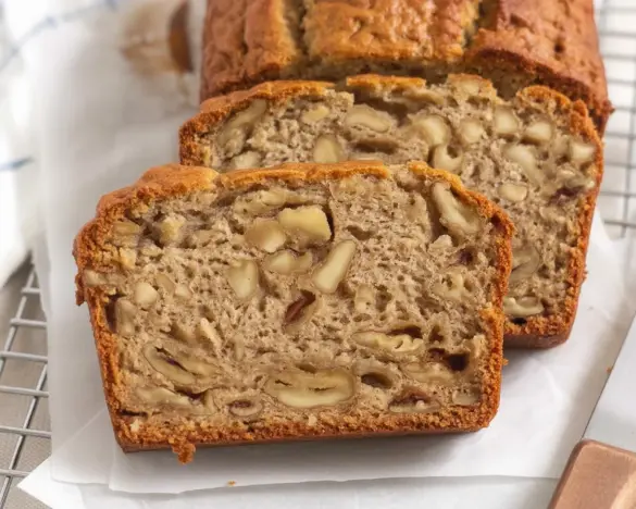 Slices of moist gluten-free banana bread with chocolate chips on a wooden table.